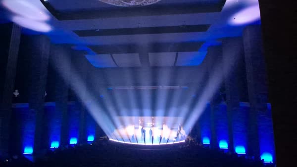 Bühnenshow in blauem Licht mit Spotstrahlen in einer Säulenhalle